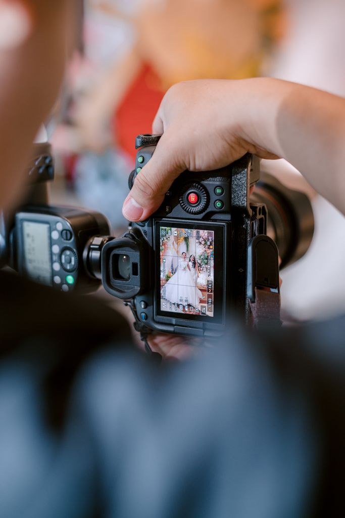 Close-up of a photographer capturing a wedding scene with a DSLR camera.